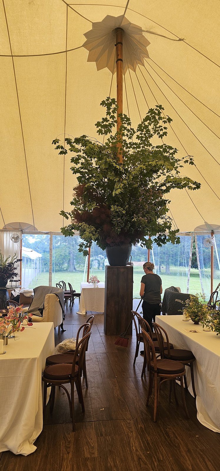 Towering branch arrangement on a custom pedestal around the center pole of a sailcloth tent